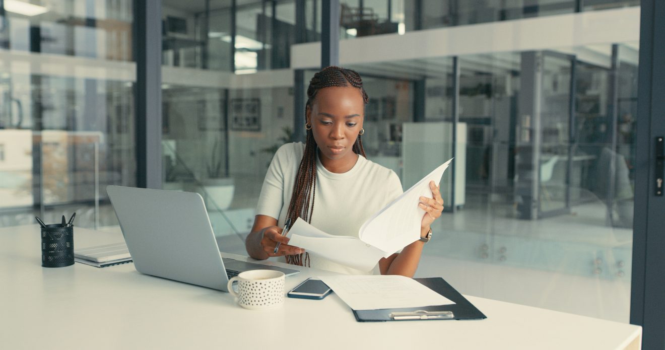 young woman doing looking at contract in front of laptop in a modern office