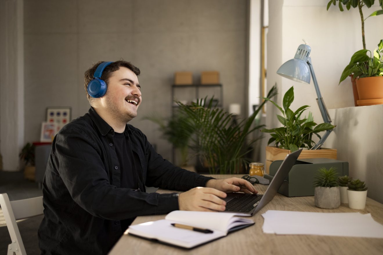 male working from home using a laptop and laughing