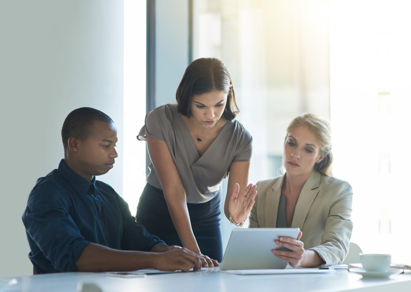 Three people discuss a project while referencing a laptop