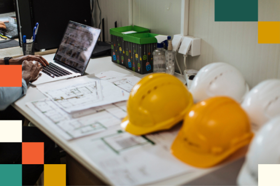 hardhats sitting on desk with construction plans