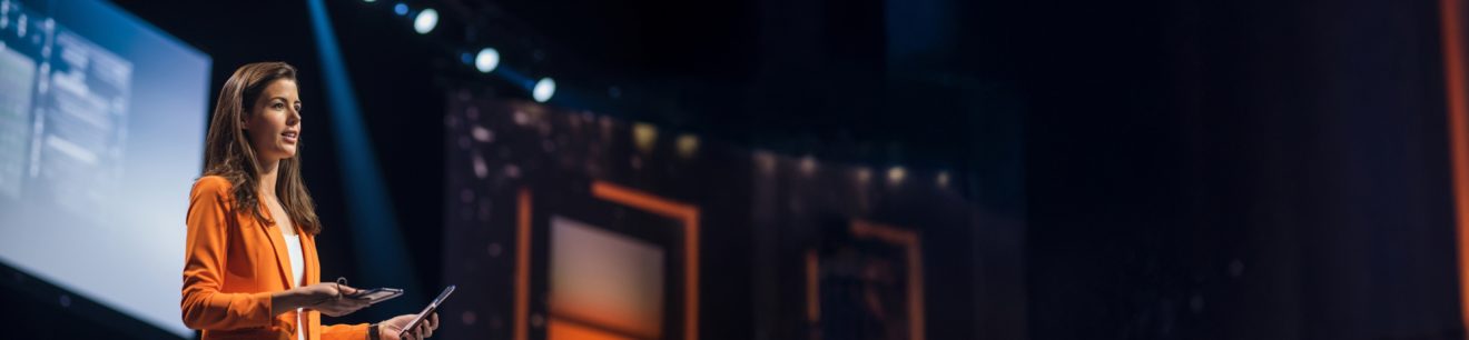 Woman speaker on stage wide