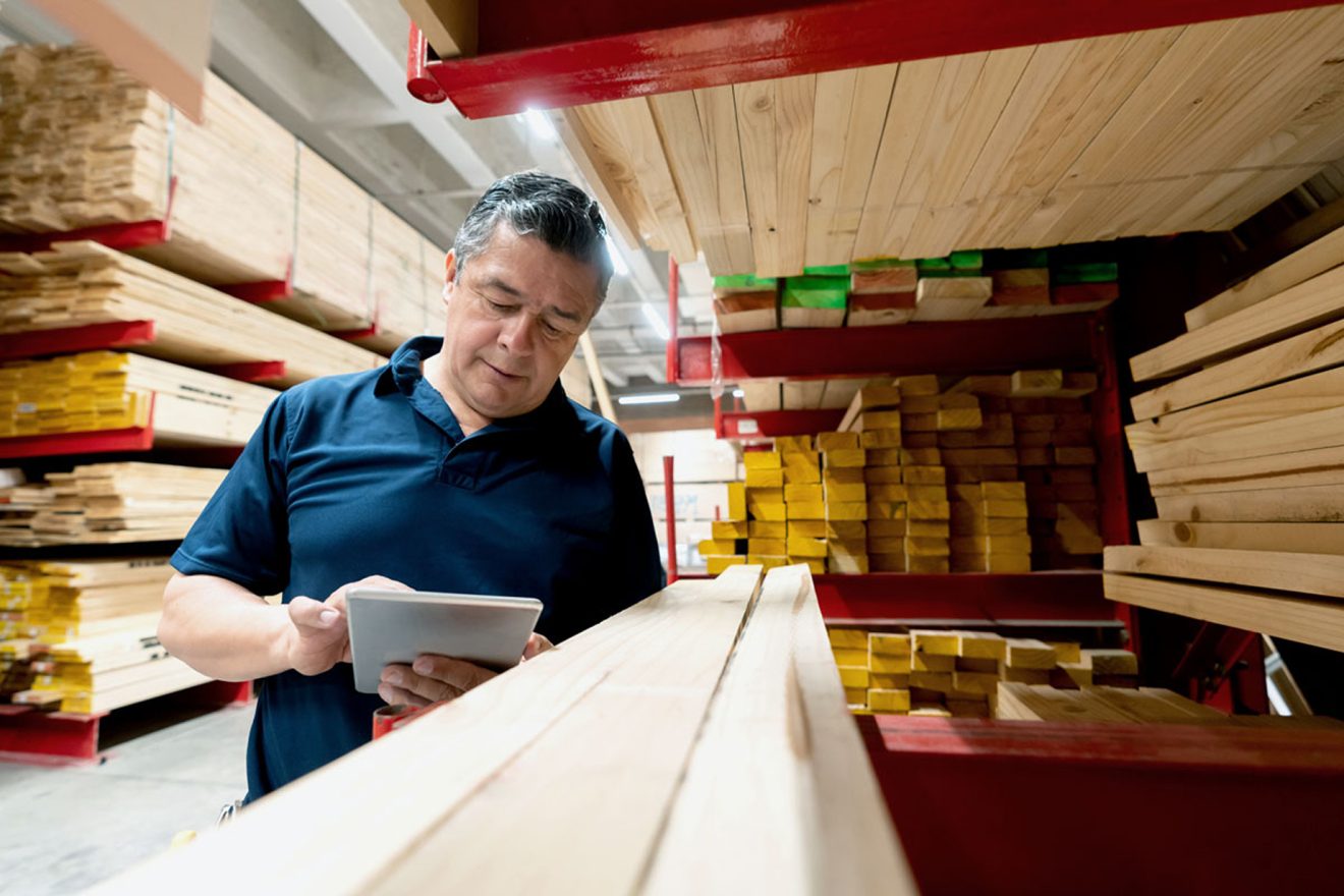 Man in a wood warehouse looking at tablet