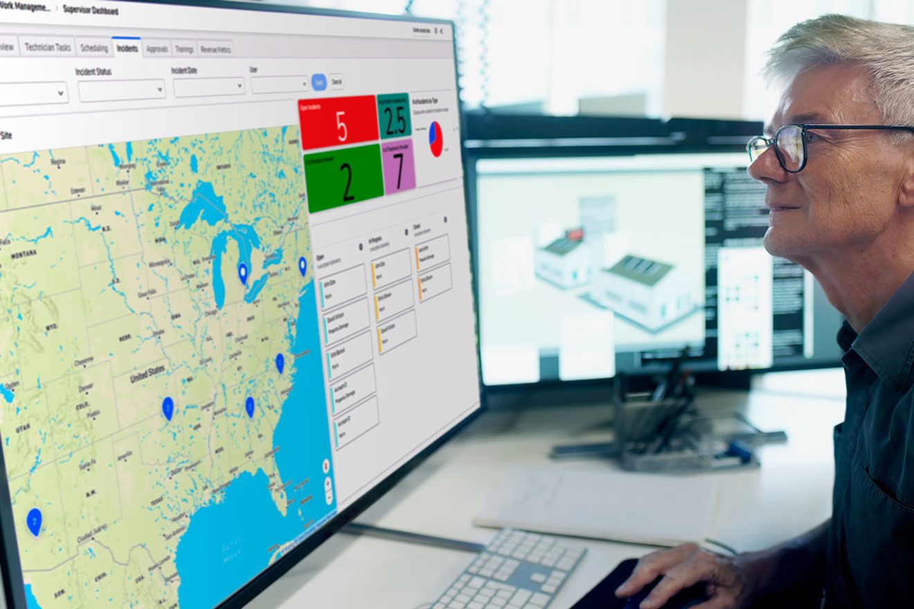 Man looking at Quickbase app with a map on a monitor