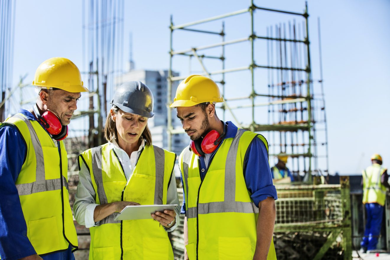 Three construction workers outside on a tablet