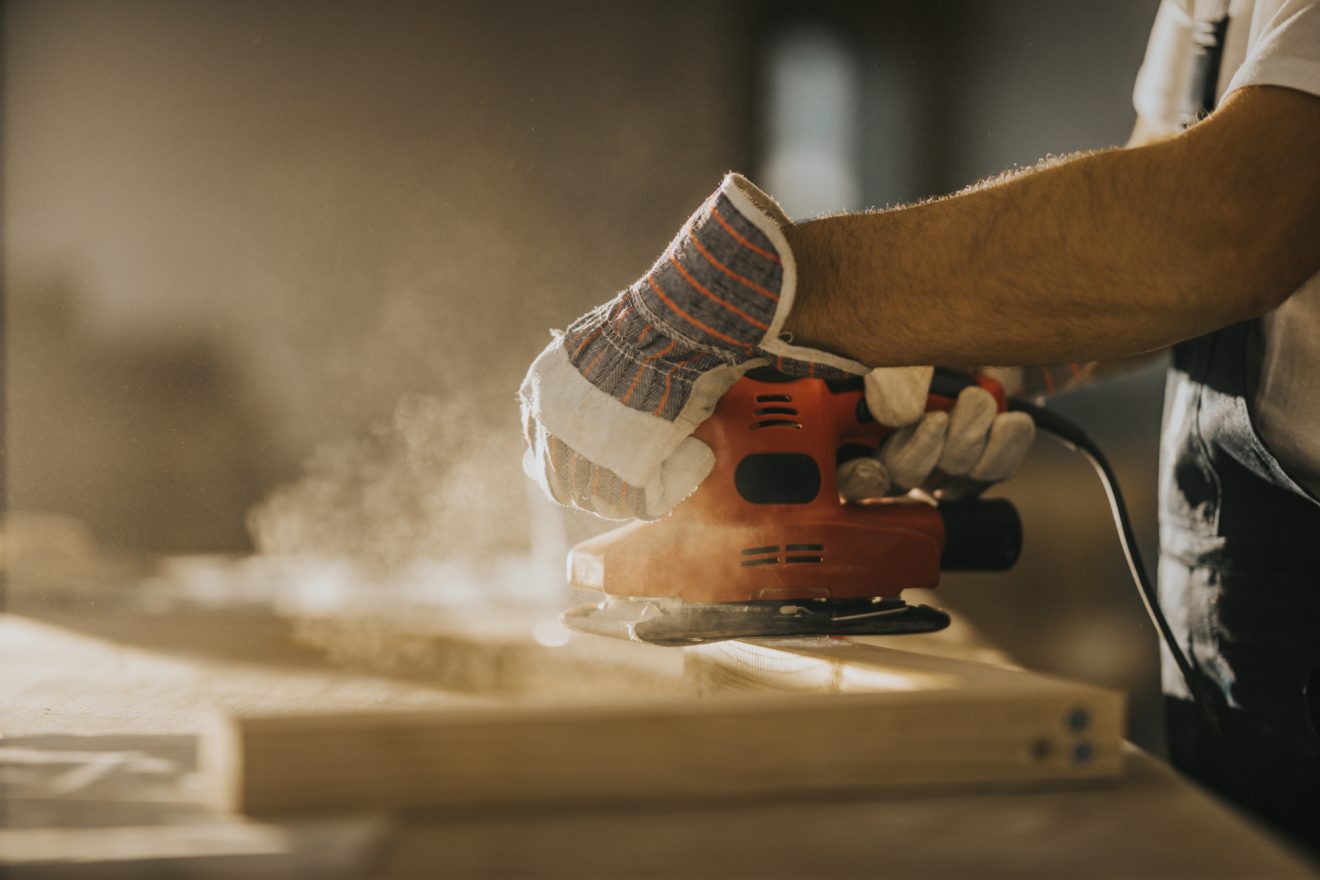 A person sands a plank of wood
