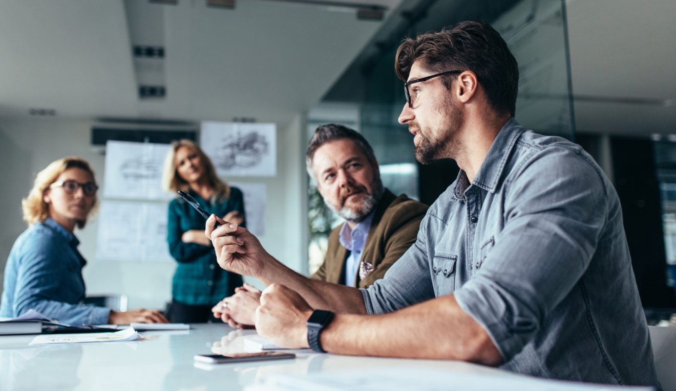 People in office gathered around a table having discussion
