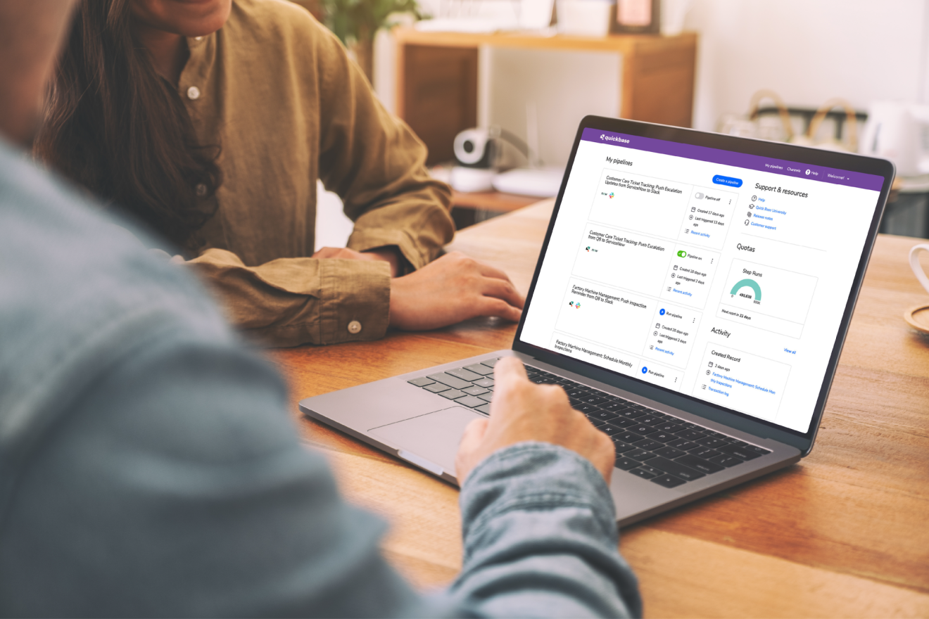 Two people build Quickbase pipelines together on a laptop